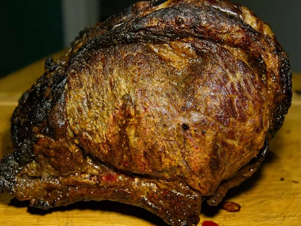 Beef prime rib roast in stages of preparation: roasted and taken out of oven for resting
