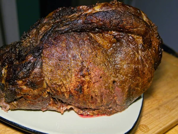 Beef prime rib roast in stages of preparation: roasted and taken out of oven for resting