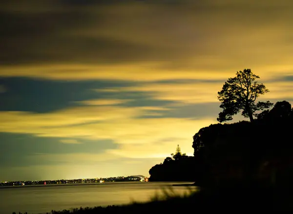 Denizin üstünde bir uçurum. Gece şehrin ışıklarıyla aydınlanıyor.