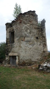 Yıpranmış bir taş harabe çimenli bir tarlanın ve yumuşak bir arazinin ortasında tek başına duruyor..