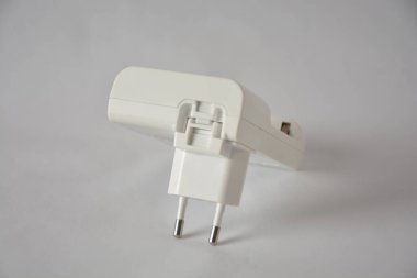 Tarafsız bir arkaplanda beyaz bir elektrik prizi adaptörü.