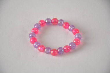 Tarafsız bir arkaplanda pembe ve mor boncuklu canlı boncuklu bilezik..