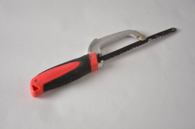 Handheld red and black hacksaw on a plain white surface. clipart