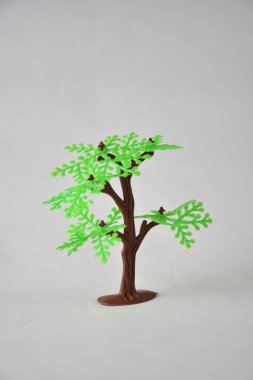 Minimalist photo of a small plastic tree branch on a pale background. clipart