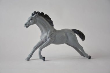 Gray plastic toy horse captured mid-gallop against a neutral background.