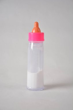Pembe şapkalı ve arka planda turuncu meme ucu olan bebek beslenme şişesi..