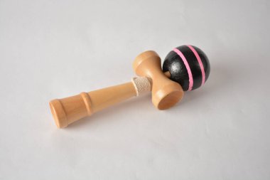 Beyaz arka planda siyah ve pembe desenli tahta kendama oyuncağı..