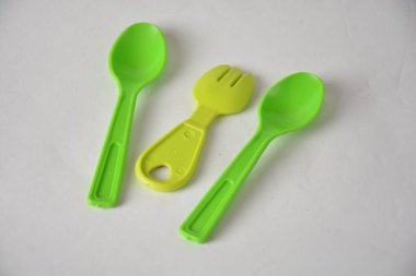 Bright green plastic spoons and fork on a white background. clipart