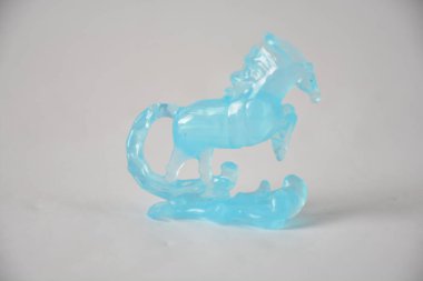 Translucent blue glass horse sculpture in dynamic pose on white background. clipart