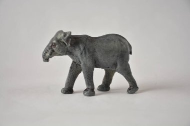 Sade bir arkaplanda dokulu gri bir yüzeyi olan minyatür bir fil heykeli..