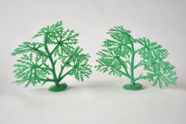 Two green plastic toy trees against a plain white background. clipart