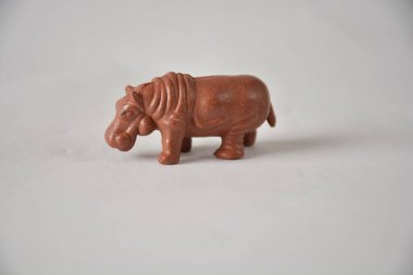 Small clay hippopotamus figurine on a light background. clipart