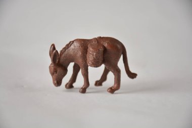 Sade bir arka planda eyer çantalı kahverengi eşek heykelciği..