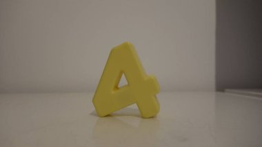 Dört numaralı sarı plastik, tarafsız bir arkaplanda pürüzsüz bir yüzey üzerinde duruyor..