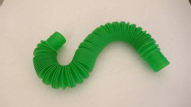 Bright green flexible plastic tube with accordion-style texture on a neutral background. clipart