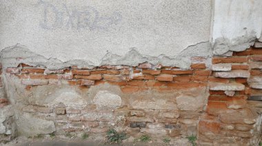 Yıpranmış tuğla duvar, alçı soyulmuş.