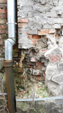 Metal boruları olan eski tuğla ve taş duvar.