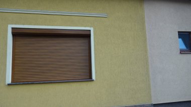 Kapalı ahşap pencereli sarı duvar.