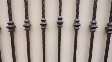 Işık duvarına dayanan süslü metal parmaklıklar