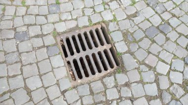 Çakıl taşı kaldırımında demir gideri kapağı..
