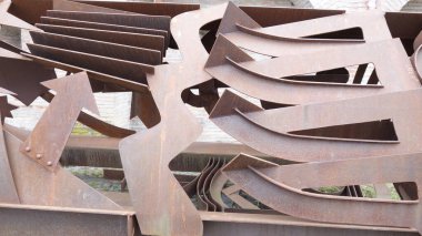 Birbirine kenetlenmiş paslanmış metal parçalarının soyut heykeli.