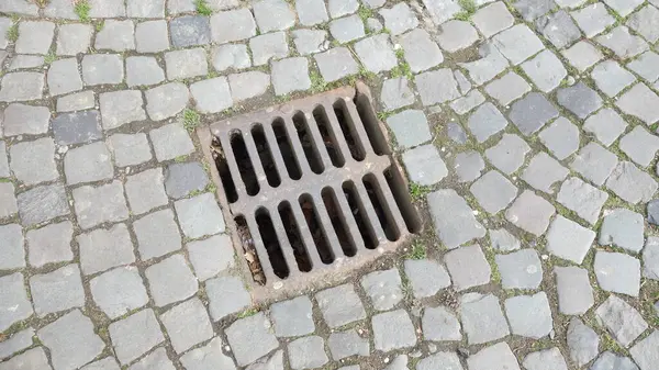 Çakıl taşı kaldırımında demir gideri kapağı..