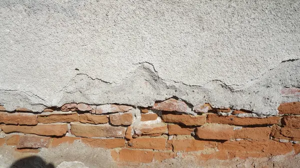 Alçı kabuğu soyulmuş eski tuğla duvar.