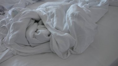 Yumuşak ışıklandırmada buruşuk beyaz yatak çarşafları