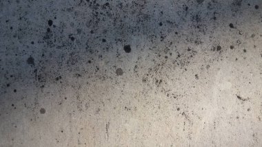 Soyut desenli, koyu lekeli beton yüzey.