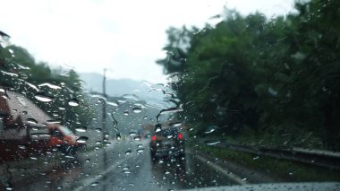 Bulanık araçlarla dolu yağmurlu yol sahnesi.