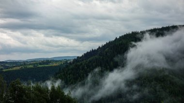 Bulutlu gökyüzünün altındaki puslu dağ manzarası