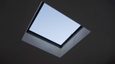 Açık mavi gökyüzü manzaralı kare tavan penceresi.