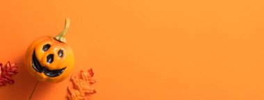 Balkabağı, sonbahar yaprakları ve fotokopi alanı ile turuncu masa zemininde yaratıcı Cadılar Bayramı tasarım konsepti