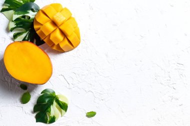 Mango arka plan tasarımı konsepti. Beyaz masa üzerinde yaprakları olan taze mango desenlerinin üst görüntüsü.