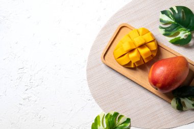 Mango arka plan tasarımı konsepti. Beyaz masa üzerinde yaprakları olan taze mango desenlerinin üst görüntüsü.