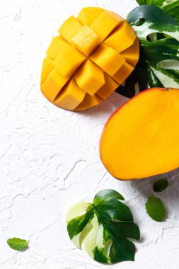 Mango arka plan tasarımı konsepti. Beyaz masa üzerinde yaprakları olan taze mango desenlerinin üst görüntüsü.