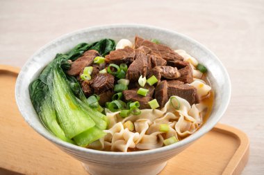 Erişte çorbası. Tayvan 'ın ünlü yemekleri dilimlenmiş kırmızı et ve sebzeler ahşap masa arkasında bir kasede..