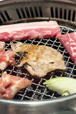 Grilling pork belly meat on a round iron BBQ net in restaurant for eating, fresh delicious food cuisine lifestyle.