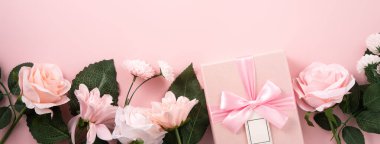 Sevgililer Günü ve Anneler Günü tasarım konsepti pembe gül, karanfil çiçeği ve pembe masa arkasında paketlenmiş hediye kutusu..