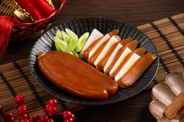 Delicious fresh mullet roe with white radish slices and garlic sprout for Chinese lunar new year gift basket box, holiday celebration.