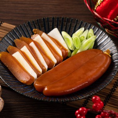 Delicious fresh mullet roe with white radish slices and garlic sprout for Chinese lunar new year gift basket box, holiday celebration.