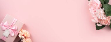 Sevgililer Günü ve Anneler Günü tasarım konsepti pembe gül, karanfil çiçeği ve pembe masa arkasında paketlenmiş hediye kutusu..