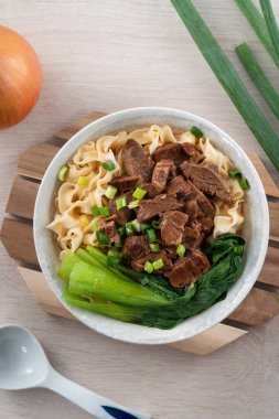 Erişte çorbası. Tayvan 'ın ünlü yemekleri dilimlenmiş kırmızı et ve sebzeler ahşap masa arkasında bir kasede..