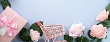 Sevgililer günü ve Anneler Günü hediye tasarım konsepti pembe gül, karanfil çiçeği ve mavi masa arkasında paketlenmiş hediye kutusu..
