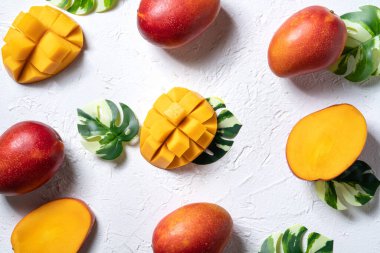 Mango arka plan tasarımı konsepti. Gri masa yaprakları ile kesilmiş taze mango desenli üst manzara.