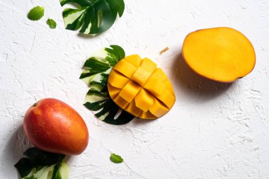 Mango arka plan tasarımı konsepti. Beyaz masa üzerinde yaprakları olan taze mango desenlerinin üst görüntüsü.
