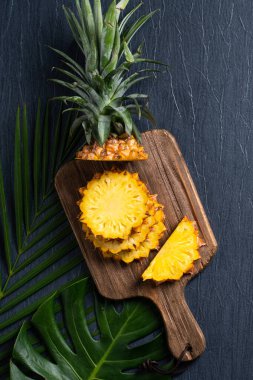 Koyu mavi arka planda tropikal yapraklı taze kesilmiş ananas manzarası.