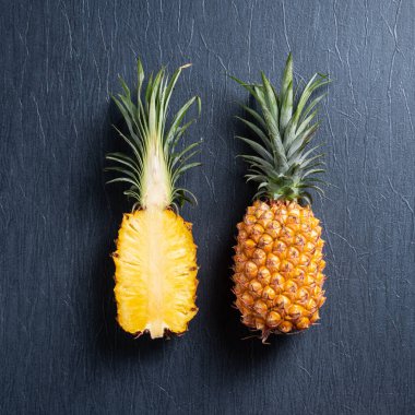 Koyu mavi arka planda tropikal yapraklı taze kesilmiş ananas manzarası.