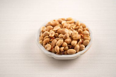 Beyaz masa arkasındaki kasede baharatlı fıstık çekirdeği..