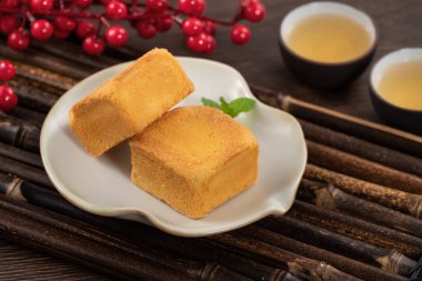 Lezzetli Tayvan usulü ananaslı pasta. Tahta bir masada tatlı. Arka planda sıcak çay var..